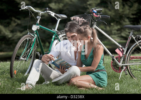 Coppia caucasica la lettura di libro in erba Foto Stock