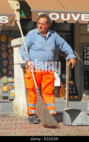 Ritratto di un pulitore di via con la scopa & pantaloni arancione a Plaza Il Campo a Siena, Italia Foto Stock