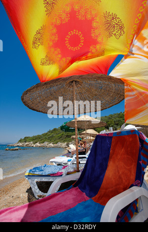 Poltrona sotto il colorato baldacchino sulla spiaggia. Villaggio di Torba, penisola di Bodrum, Turchia. Foto Stock