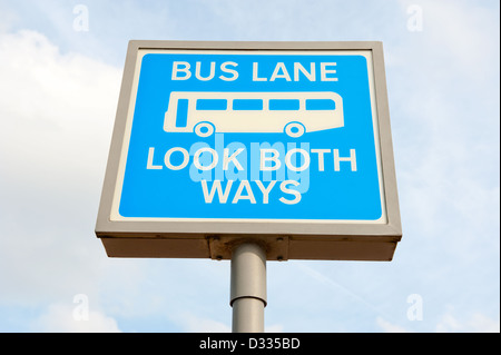 Basso angolo di visione di un segno di avvertimento per i pedoni "guardare in entrambe le direzioni' come appena davanti è una corsia degli autobus. Foto Stock