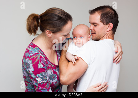 Ritratto di famiglia felice che trasportano simpatico baby boy, isolato su sfondo neutro. Foto Stock