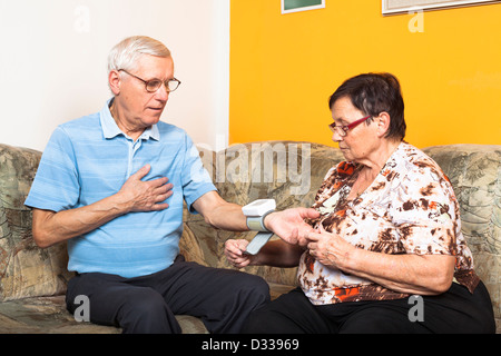 Coppia senior controllando la pressione del sangue a casa. Foto Stock