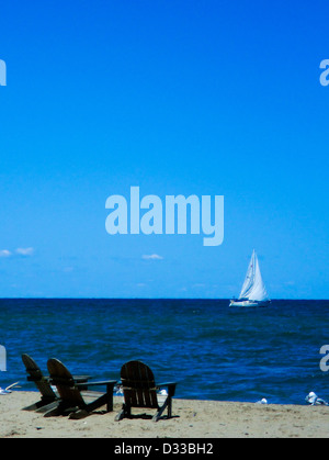 Adirondak sedie a sdraio sulla spiaggia che guarda al cielo azzurro e bianco in barca a vela su un blu brillante Lago Erie orizzonte al di fuori di Cleveland Foto Stock