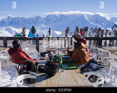 La gente gli sciatori seduti fuori Les Grandes Platieres ristorante di montagna in Le Grand Massif ski area con vista di Mont Blanc nelle Alpi francesi, Francia Foto Stock