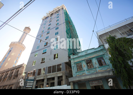 Alto edificio in costruzione, accanto a un 1930 Indian Building e moschea, Dar es Salaam, Tanzania. Foto Stock