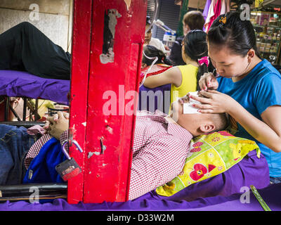 Febbraio 2, 2013 - Phnom Penh Cambogia - un uomo ha la sua sopracciglia tweezed in un salone di bellezza in un mercato in Phnom Penh Cambogia. (Credito Immagine: © Jack Kurtz/ZUMAPRESS.com) Foto Stock