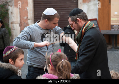 Uomo ebraico si prepara a pregare con tallit e Tefillin al Ghetto di Roma. Foto Stock