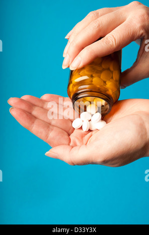 Donna versando pillole di un farmaco bottiglia nella sua mano Foto Stock