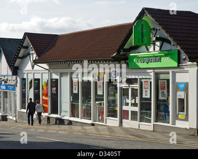 Coppia giovane camminando passato co-operativa in negozio Bowness, Parco Nazionale del Distretto dei Laghi, Cumbria, England Regno Unito Foto Stock