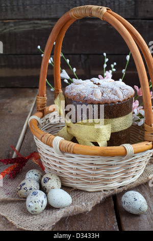 Tradizionale torta di Pasqua nel cesto con uova di quaglia sul tavolo in legno in stile rustico Foto Stock