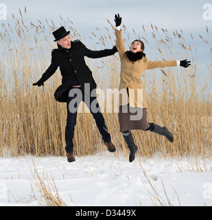 Felice l'uomo e la donna salta sul lago spiaggia Foto Stock