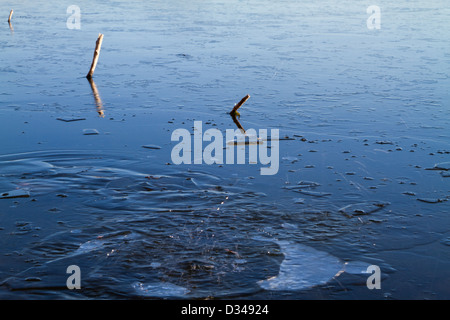 Rock a cadere attraverso il ghiaccio in un lago Foto Stock