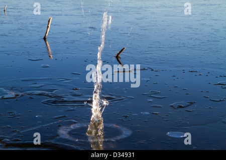 Rock a cadere attraverso il ghiaccio in un lago Foto Stock