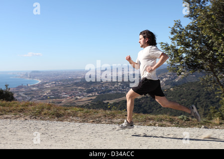 Uomo che corre su un percorso con il centro di Barcellona in background Foto Stock