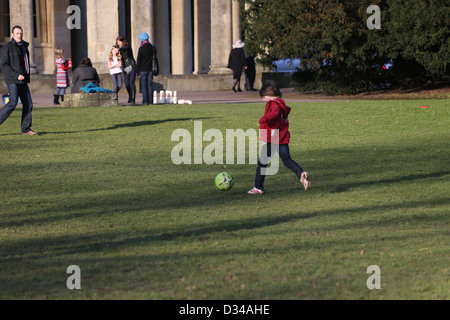 Padre e Figlio a giocare a calcio all'Pittville Pump Room Pleasure Gardens Cheltenham Gloucestershire in Inghilterra Foto Stock