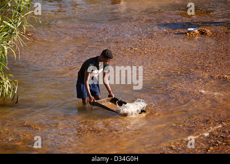 Madagascar, Ilakaka, Sapphire città mineraria, uomo panning per gemme in fiume Foto Stock