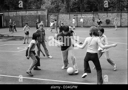 Ragazzi e ragazze delle scuole che giocano a football nel parco giochi delle scuole medie pausa pranzo South London Inghilterra anni '1975 1970 UK HOMER SYKES Foto Stock