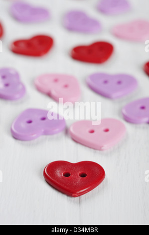 Rosso, rosa e viola i pulsanti a forma di cuore in bianco sullo sfondo di legno Foto Stock
