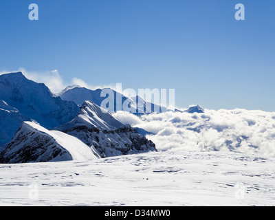 Vista da Les Grandes Platieres in Le Grand massiccio a montagne dalle vette innevate sopra la nuvola in valle nelle Alpi francesi. Flain Francia Foto Stock