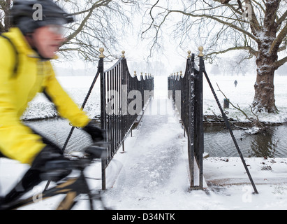Ferro decorativo ponte che attraversa un canale che corre vicino al Tamigi e la coperta di neve Old Deer Park in inverno, Richmond Upon Thames, Surrey Foto Stock