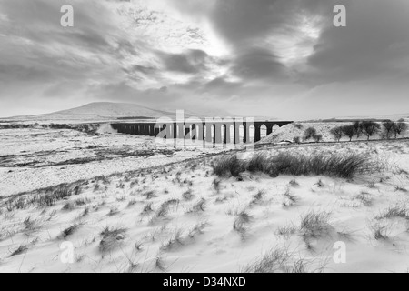 Immagine in bianco e nero del viadotto Ribblehead in inverno con neve sul terreno e Ingleborough avvolta nella nebbia e cloud. Foto Stock