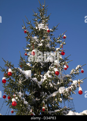 Un enorme albero di natale con grandi palle rosse e la decorazione sul cielo blu Foto Stock