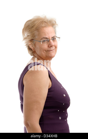 Fiducioso donna di mezza età che indossa un viola camicia senza maniche e guardando sopra la sua spalla destra isolati su sfondo bianco Foto Stock