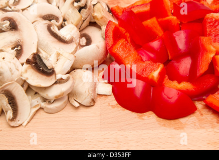 Fresche tagliate i funghi e peperoni rossi sul tagliere di legno Foto Stock