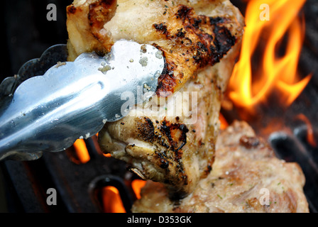 Flaming cosce di pollo alla griglia Foto Stock