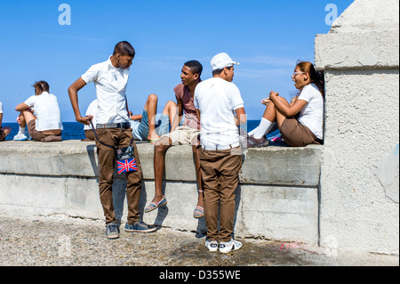 I bambini delle scuole su una pausa seduto e in piedi intorno alla parete del mare a le Malecon, Havana, Cuba. Foto Stock