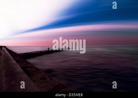 Vista panoramica con paesaggio distorto e sky con stagliano figure di pesca sul molo Foto Stock