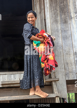 Giovane donna porta servizio lavanderia, uno di Cham persone che vivono in un villaggio lungo il fiume Mekong a sud di Kratie, Cambogia. Foto Stock