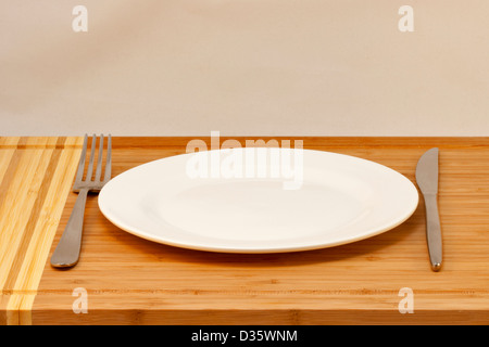 Posate la piastra a vuoto, tavola coltello e forchetta su una scrivania in legno Foto Stock