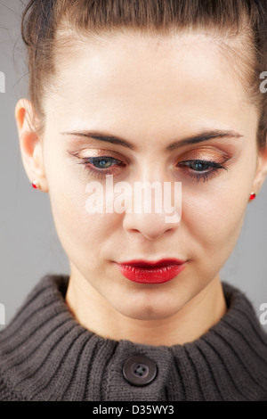 Ritratto di una giovane e bella donna con occhi blu isolato su grigio Foto Stock