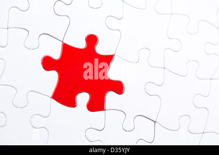 White jigsaw puzzle con un pezzo di rosso Foto Stock