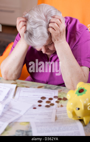 Donna anziana si siede di fronte a carte e disperata Foto Stock