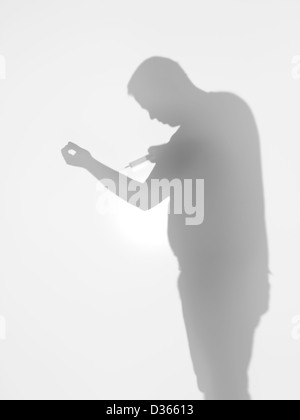 Vista laterale di uomo con una siringa verso il suo braccio dietro una superficie diffusa Foto Stock