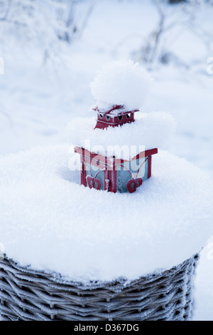 Lanterna rossa in appoggio in pieno di neve cesto in vimini all'aperto sul giorno di inverno Foto Stock