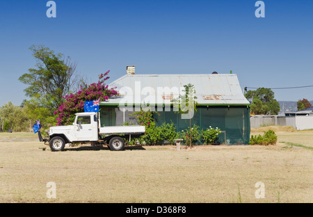 Vecchia casa con una Toyota Landcruiser tray top ute decorate con bandiere australiano circondato da erba secca in Australia Occidentale Foto Stock