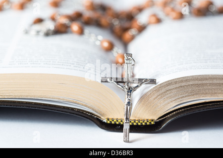 Croce di rosario in appoggio contro la bibbia Foto Stock