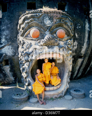 Laos, Vientiane, Buddha Park, monaco buddista novizi nel demone bocca della zucca gigante scultura a Wat Xieng Khuan Foto Stock