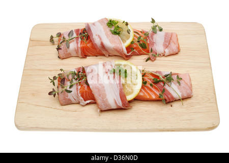 Filetti di salmone preparato con pancetta, limone e timo ona tavola di legno isolata contro bianco Foto Stock