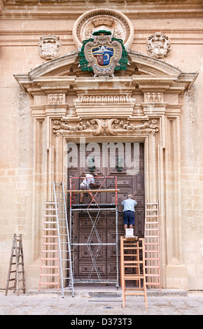 Operai ripristinando la grande porte alla Cattedrale di San Paolo a Mdina, Malta. Foto Stock