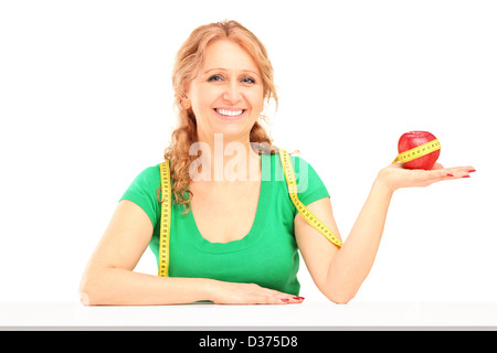 Sorridente donna matura azienda red apple e nastro di misurazione, isolati su sfondo bianco Foto Stock