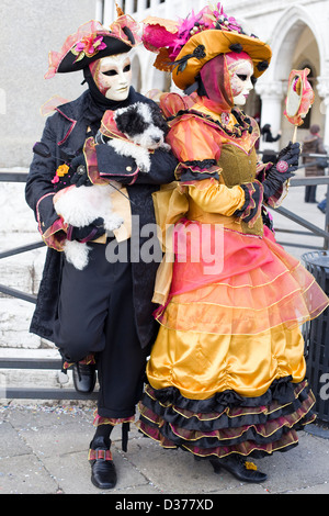 Gentleman e Lady tenendo un cane vestito in costume veneziano su di un ponte a Venezia Italia Foto Stock