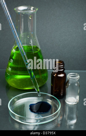 Becher di laboratorio riempito con il colore verde di sostanze liquide e laboratorio di una pipetta. Sfondo scuro Foto Stock