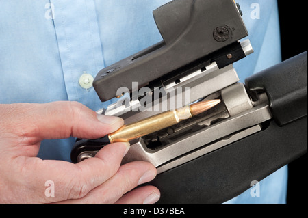 Un imprenditore che indossa un abito shirt carichi un fucile da assalto con un singolo 223 bullet Foto Stock