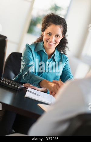 Stati Uniti d'America, New Jersey, Jersey City, Donna agitando la mano con Uomo alla scrivania Foto Stock