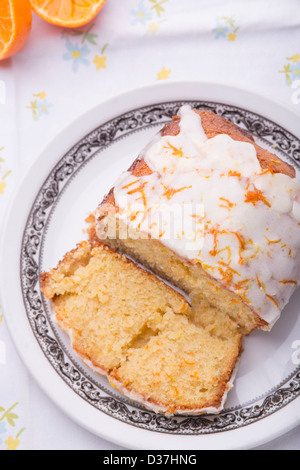 Citrus lemon orange clementina pioggerella ghiacciata di pan di spagna in casa su una tovaglia floreale con un Clementina. Foto Stock