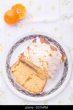 Citrus lemon orange clementina pioggerella ghiacciata di pan di spagna in casa su una tovaglia floreale con un Clementina. Foto Stock